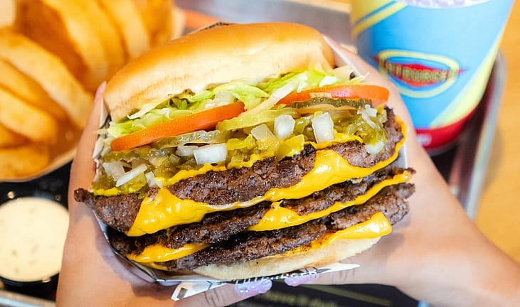 Hand holding a massive cheeseburger from Fatburger
