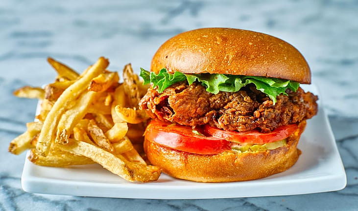 A fried chicken sandwich and fries on a plate.