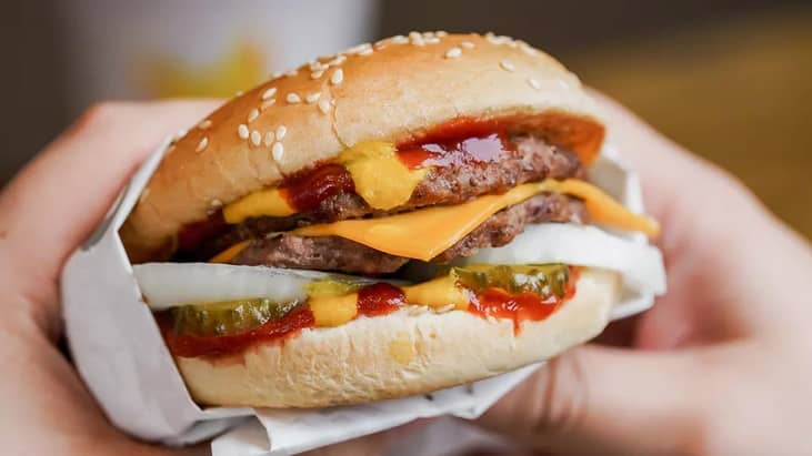 Two hands holding a cheeseburger.