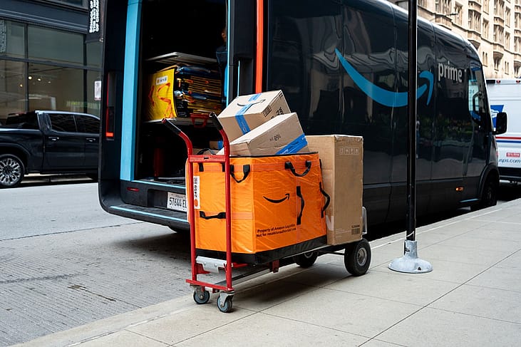 Amazon packages on a hand truck next to an electric Amazon delivery truck in Chicago.