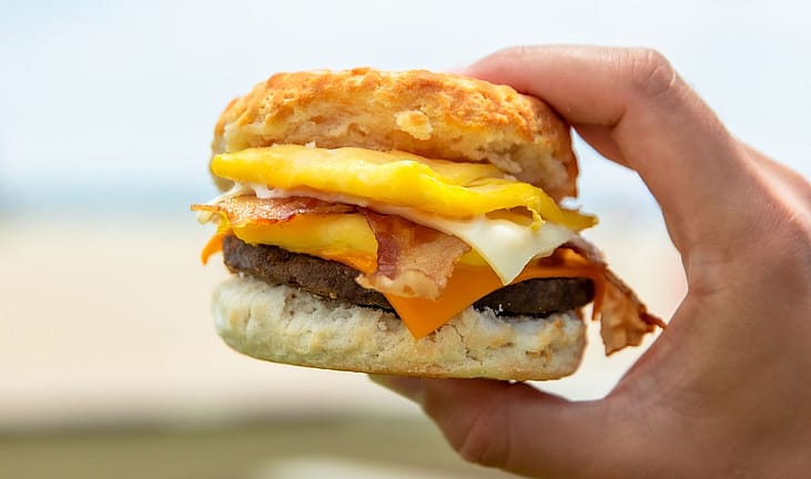 Hand holding a breakfast sandwich.