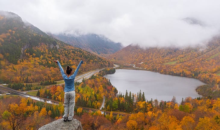 Woman posing in front of beautiful Echo Lake from Artists Bluff Loop in New Hampshire.