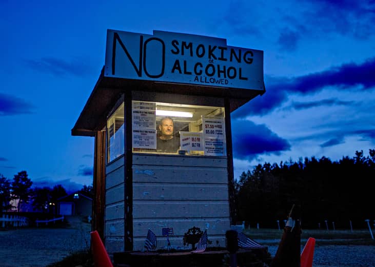 The owner of the Bridgton Twin Drive-In waits for patrons at the front gate.
