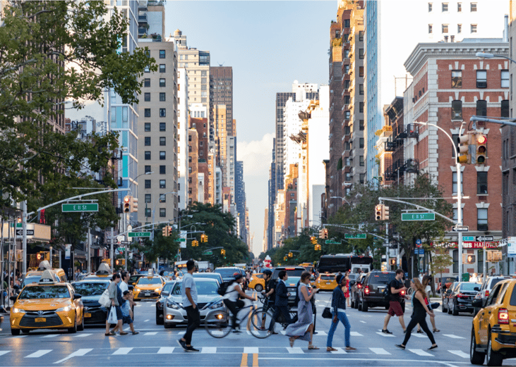 Crowds of people walk across 3rd Avenue in Manhattan.