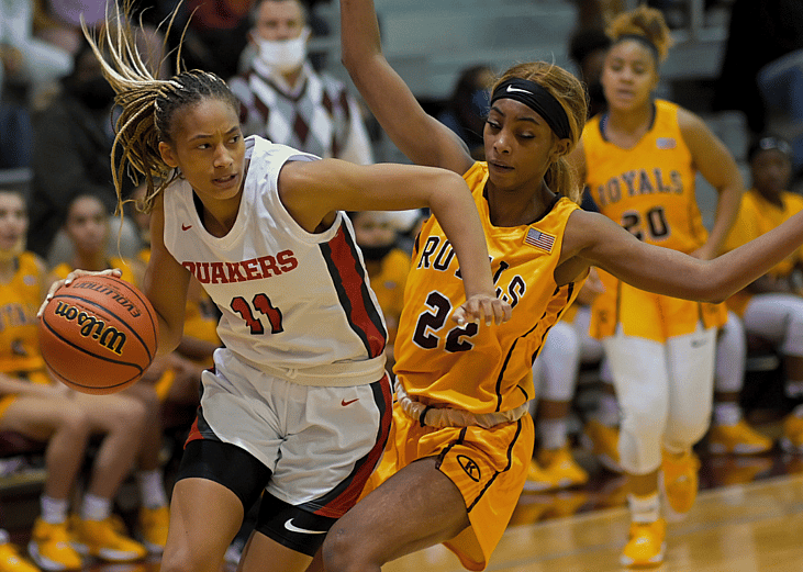 Two basketball players on a basketball court during girls basketball tournament. 