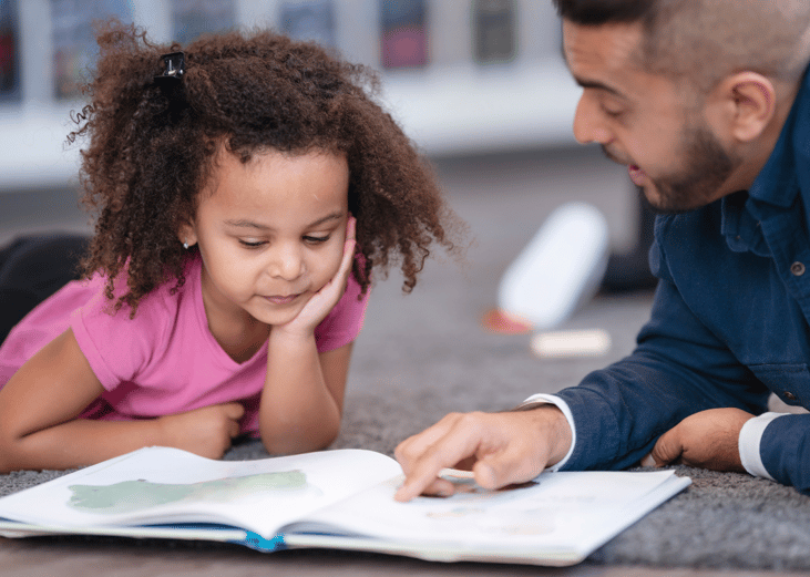 A kindergarten teacher reading a book to a student.