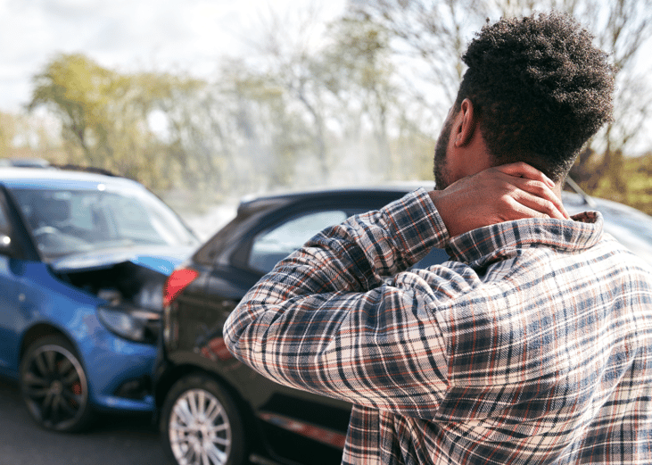 A person looking at their car, which has been rear-ended by the vehicle behind it.
