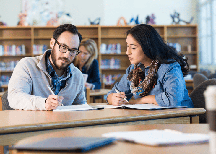 Two college students studying together in a classroom.