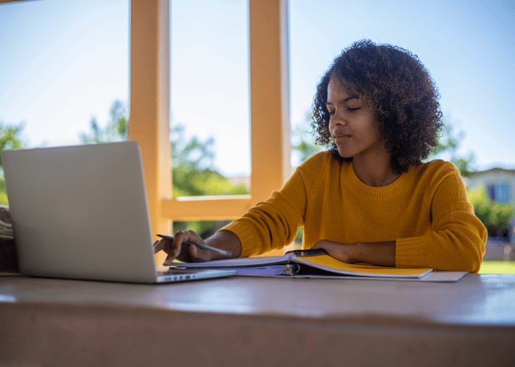 A college student on their laptop in a library.
