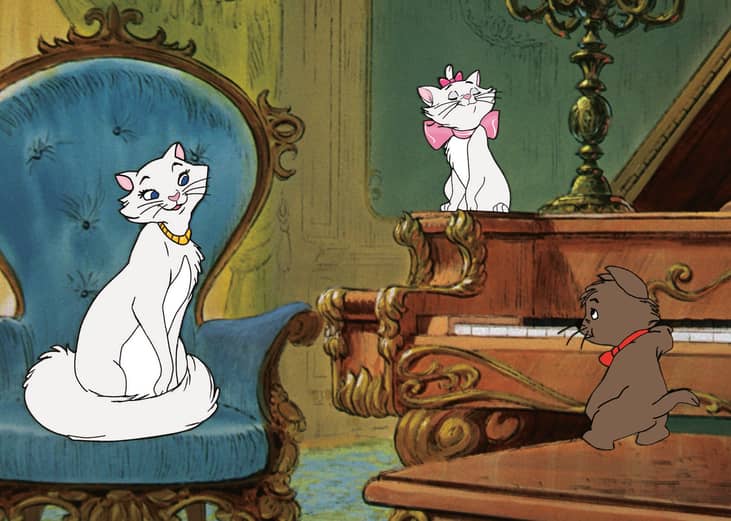 Two white cats listen to a small brown cat play the piano.
