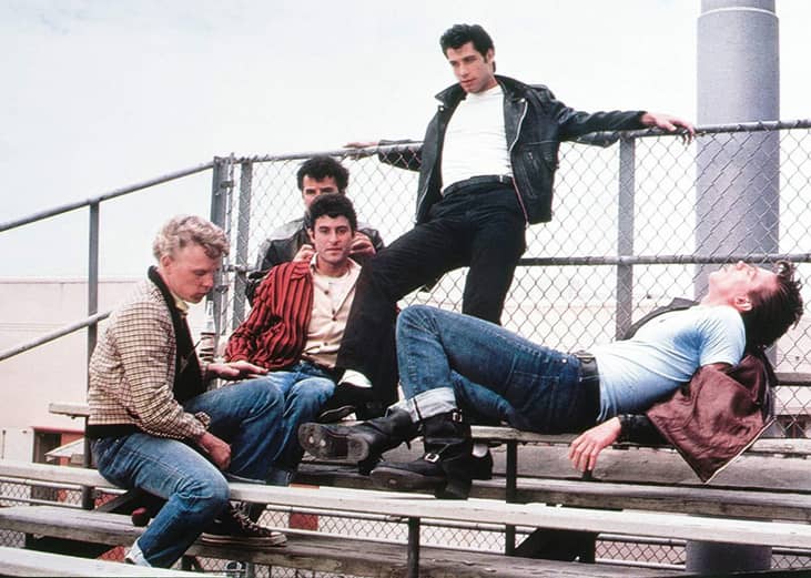 John Travolta and a group of guy friends hanging out on the bleachers.