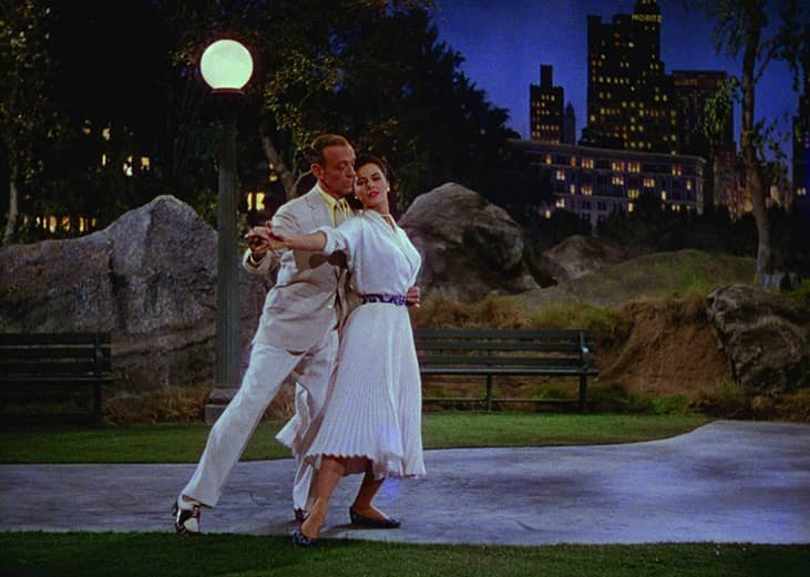 Fred Astaire dancing outside with a woman under a streetlight.