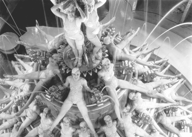 Dancers posing stacked up a tiered stage.