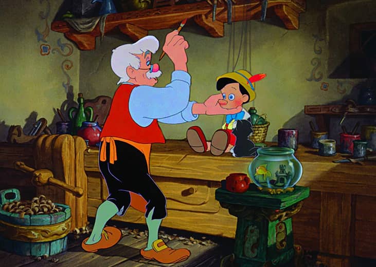 A cartoon of a man painting a puppet that he made.