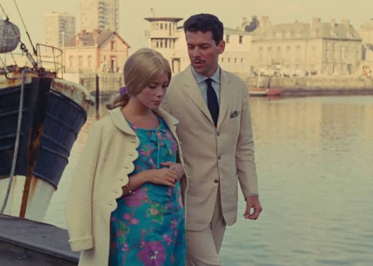 A man and woman walking along the water.
