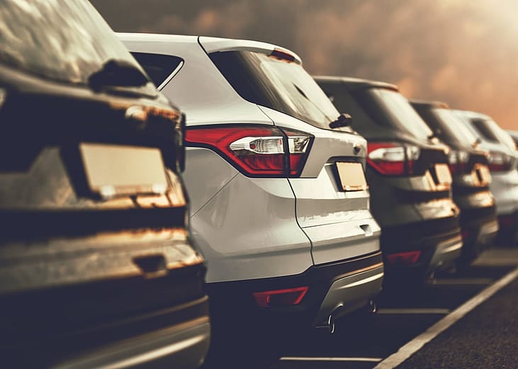 A line of small SUV's with ominous sky in background.