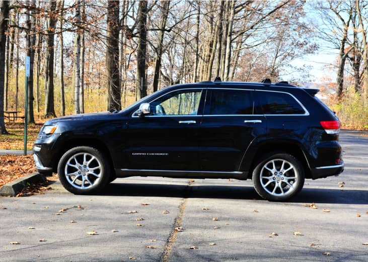 Black Jeep Cherokee SUV in tree-lined parking lot in Farmington, Wisconsin.