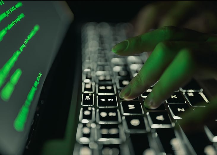 Fingers on a computer keyboard with dark background.