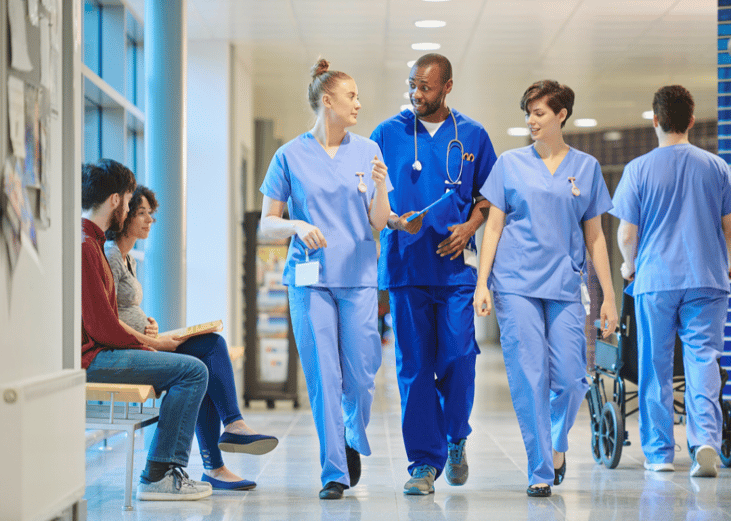 Hospital staff in blue scrubs walking down a hallway.