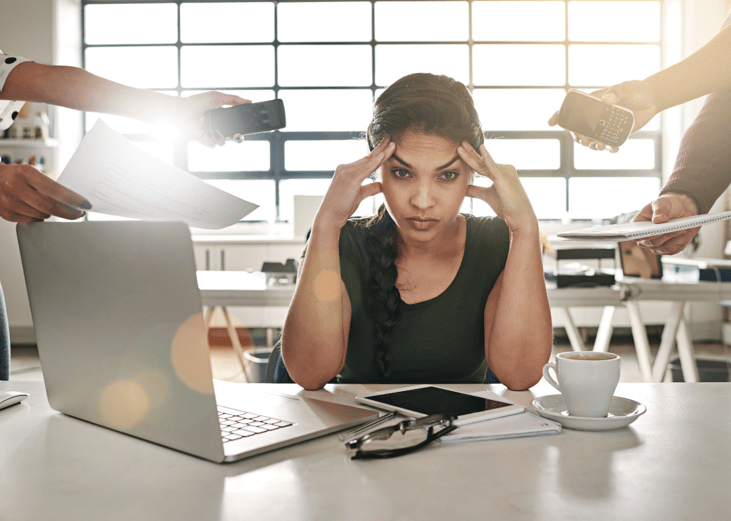 A stressed woman at a desk with hands coming at her from all sides with phones and tasks.