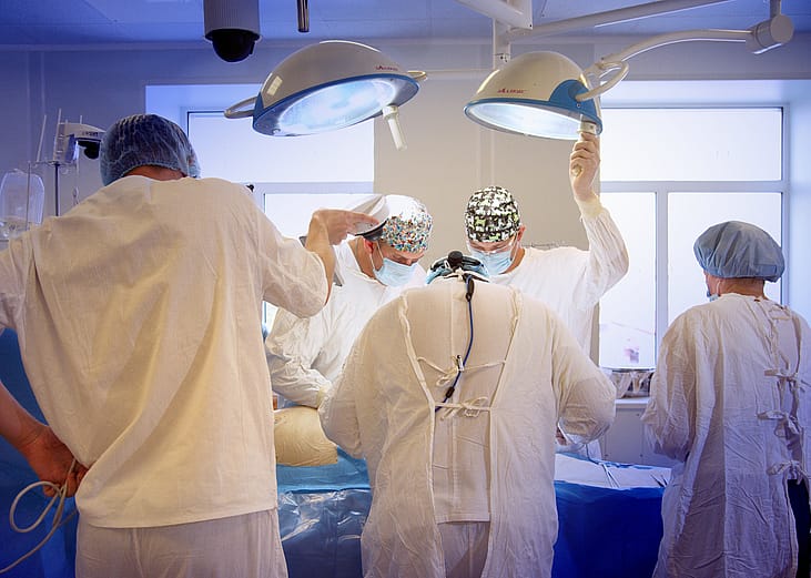 Masked surgeons perform surgery.