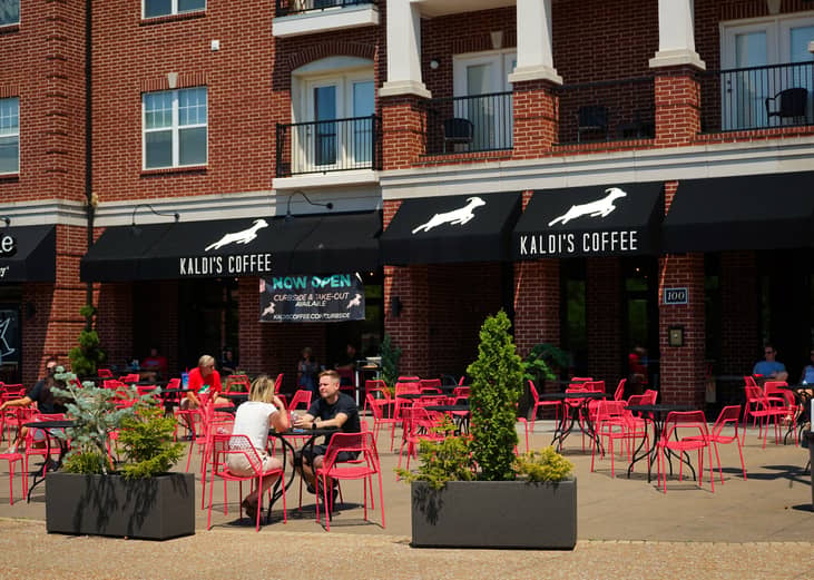 People sitting at tables on a patio outside coffee shop