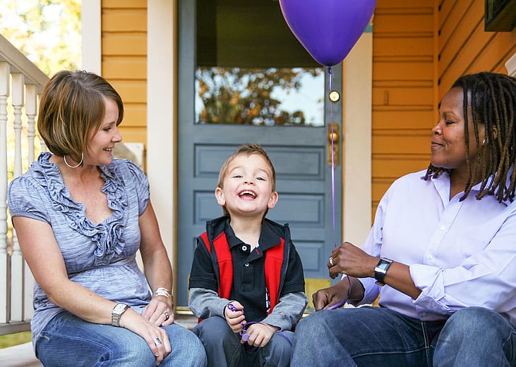 Two women and their son sitting on porch