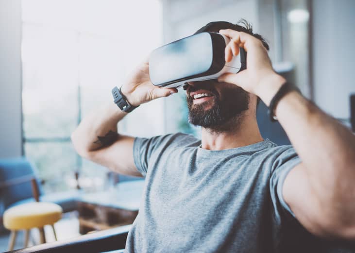 Bearded man wearing virtual reality goggles.