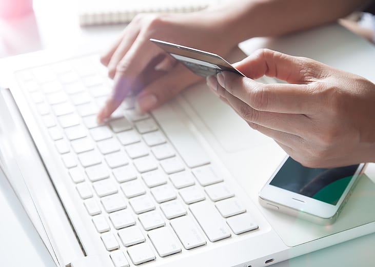 Hand holding credit card and using laptop