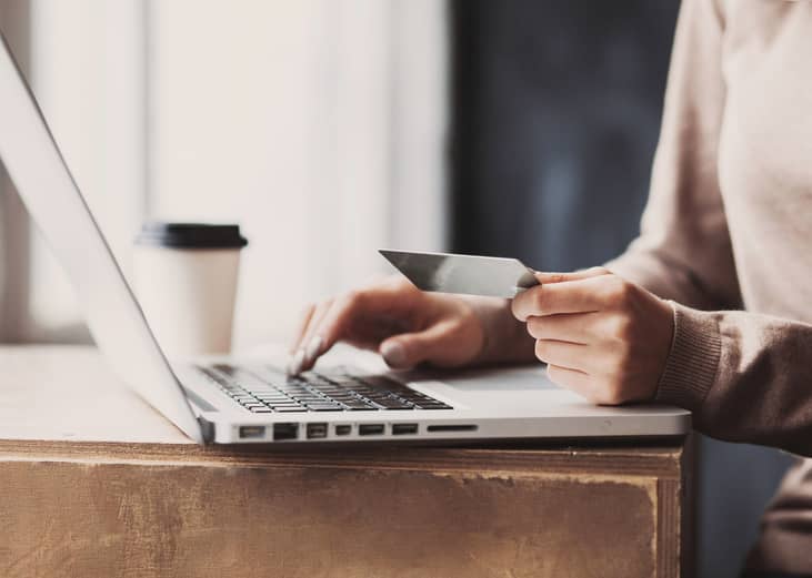Woman hand holding credit card and using laptop.