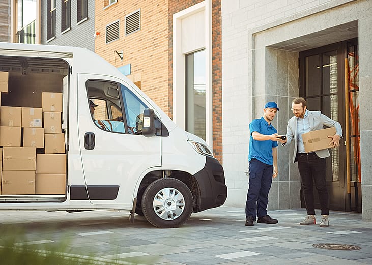 Delivery man gives postal package to its consignee in a business address.