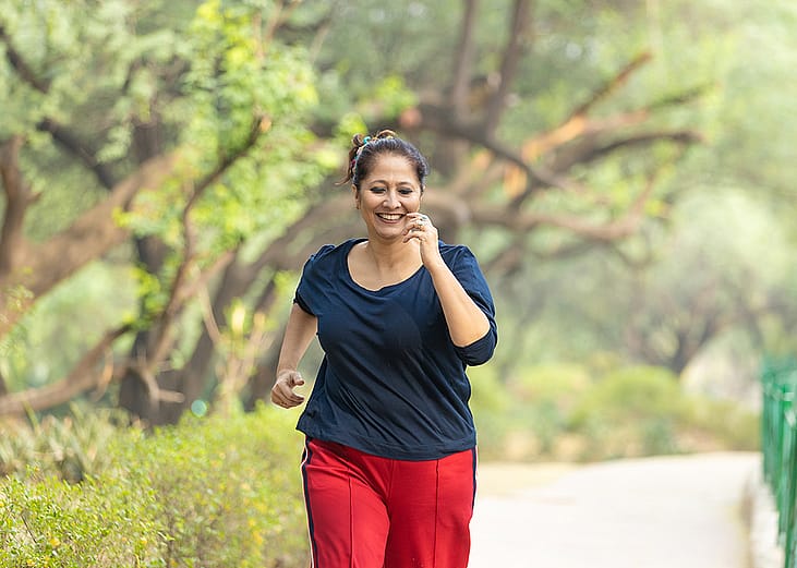 A middle-aged woman jogging at the park.