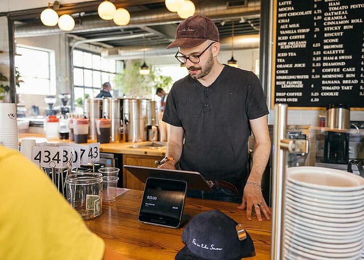 A restaurant staff mans the cashier and inputs order from a customer.