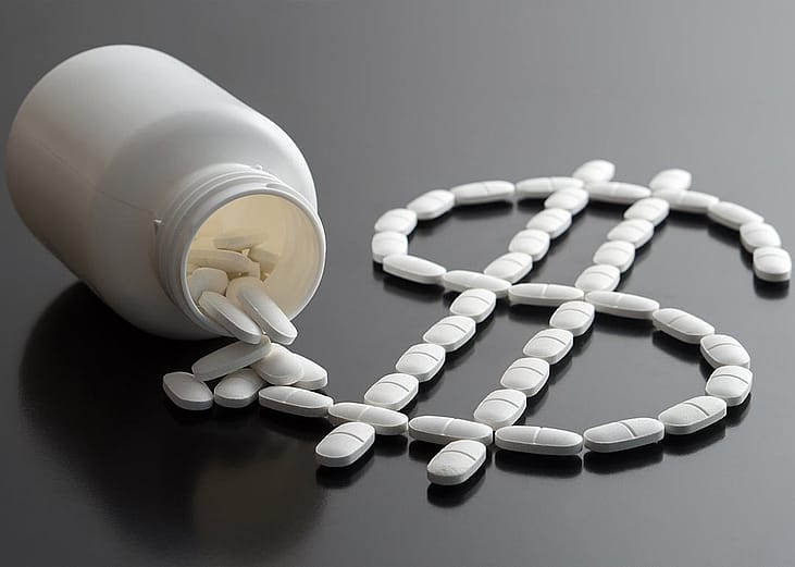 Pills from a bottle forming a dollar sign as a concept of rising medicine costs.