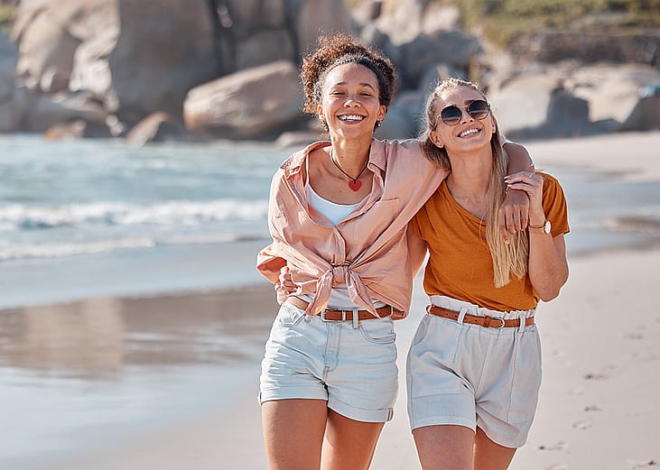 A happy lesbian couple walking on the beach.
