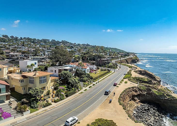 Aerial view of hillside luxury single family homes above Sunset Beach, San Diego with palm trees and terraces.