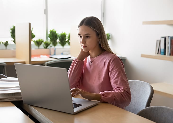 Young college student using a laptop to browse through finances.