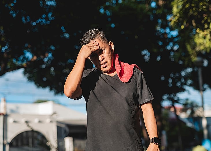 A middle-aged Southeast Asian man walking on a hot day after exercise.