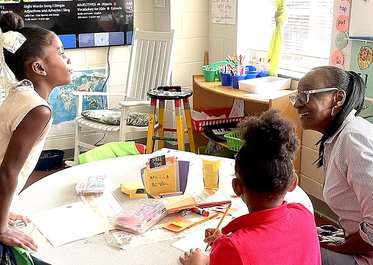 Volunteer Gae Bryant, right, works on a drawing exercise with two students in the K-2 class at The Ferguson School, a microschool that meets in an Atlanta-area church.