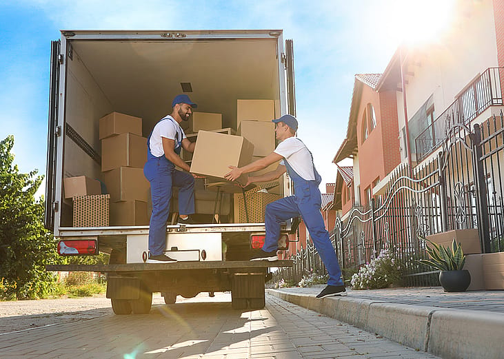 Two workers unloading boxes from a truck servicing a relocation.