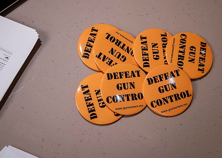 Orange "Defeat gun control" buttons set out on a table for people after they sign their name to give to legislators working on gun control bills.