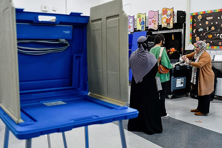 An election official assists voters ready to turn in their ballots for the US presidential and congressional elections at Dearborn High School in Dearborn, MI, United States on November 05, 2024.