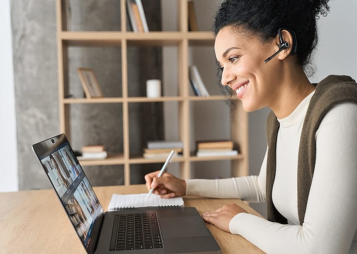 Young female professional engaged in a virtual meeting while working from home.