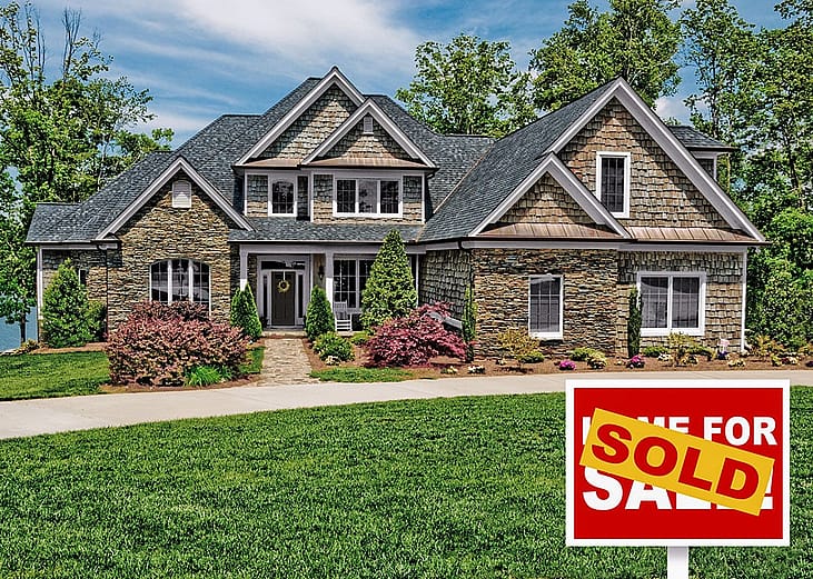 Home with green lawn and "For sale" sign covered by the word "sold."