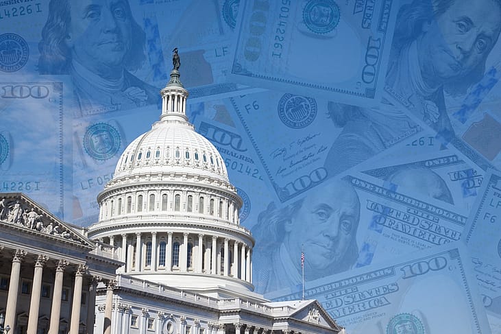 Cutout of U.S. capitol with 100 dollar banknotes layered over the blue sky.