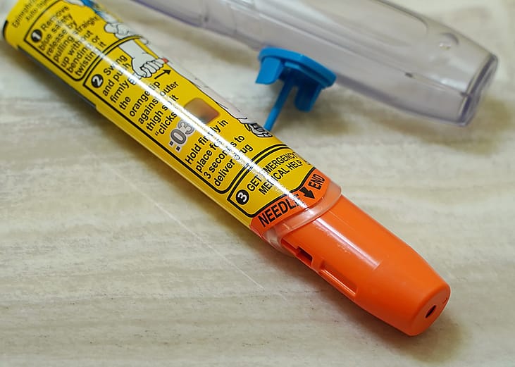 A discarded Epipen auto injector lying beside a sink.