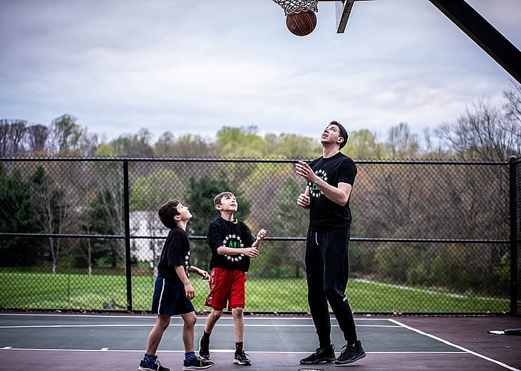 A private sports coach in a basketball session with two young boys.