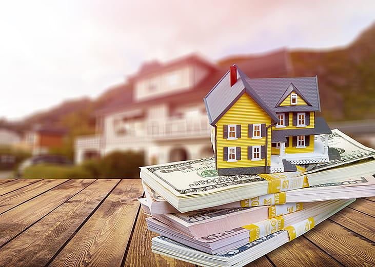 A figure of a house on top of bundles of cash.