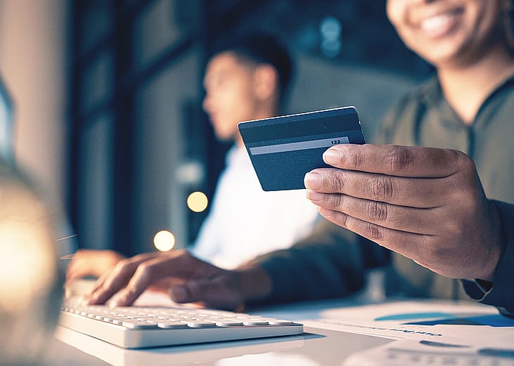 An employee holding a credit card while making an online purchase in the office.