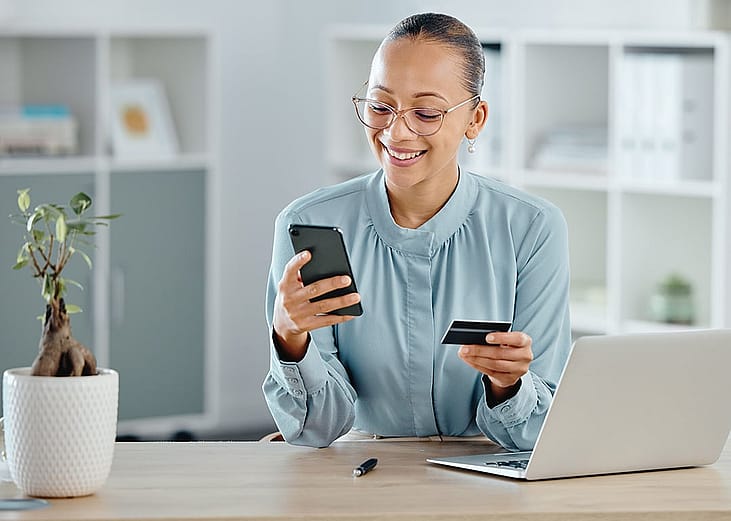 A female business professional using a credit card for an online purchase while working.